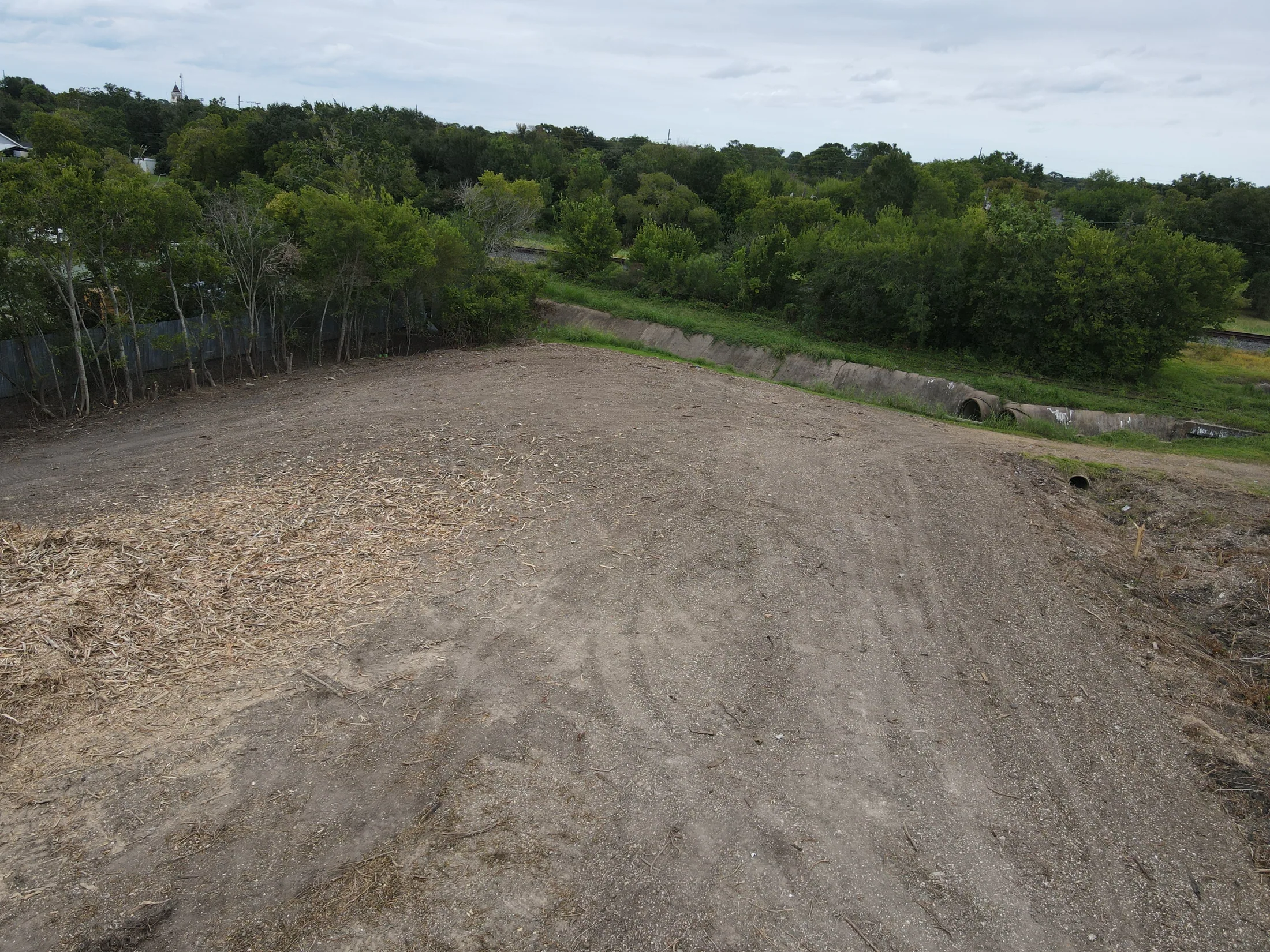 Cleared ground and equipment tracks bordered by retained trees