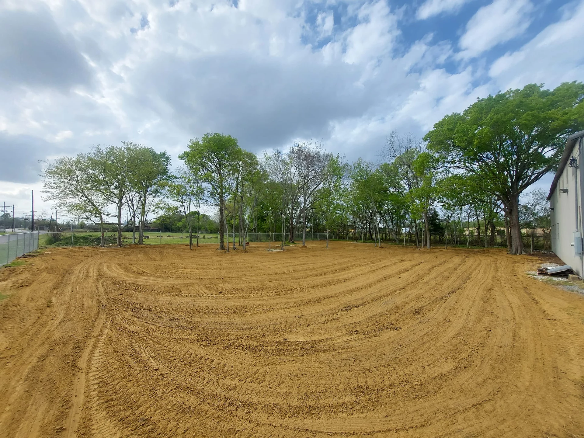 Broad graded dirt site beside an existing metal building