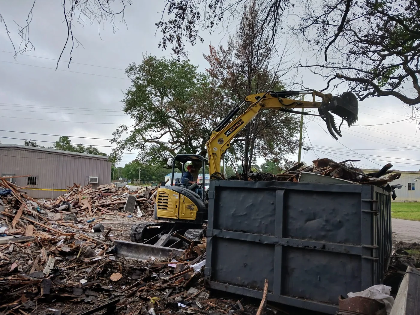 Excavator loading timber and demolition debris into a steel container