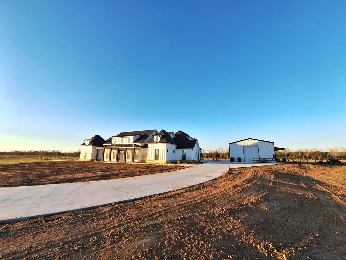 Shaped soil around a residential driveway with a home and metal shop beyond